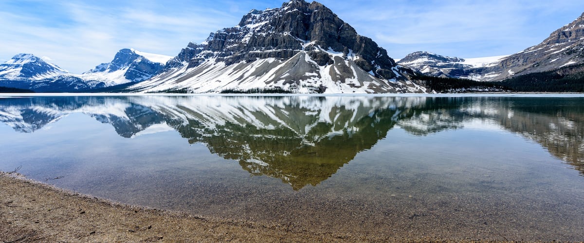 A mountain reflection in a calm lake with clear skies.