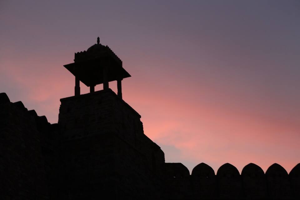A silhouette of a structure against a sunset sky.