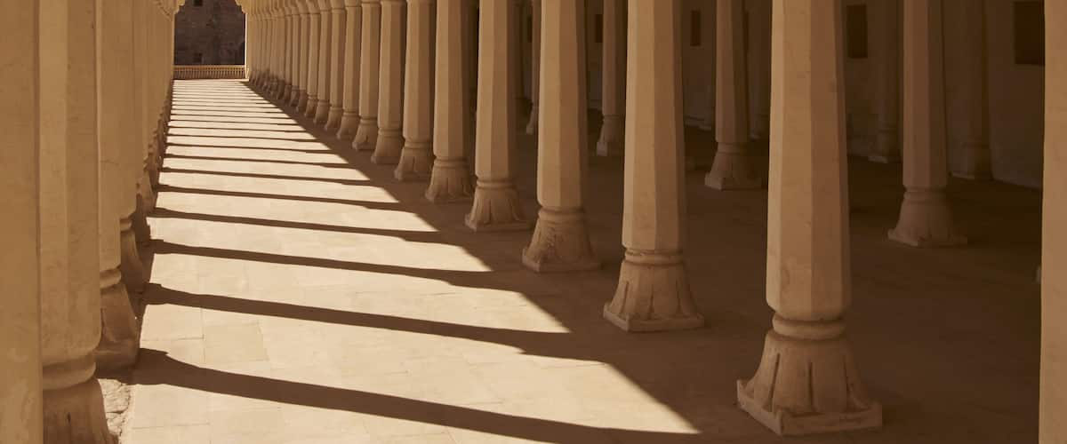 A corridor with rows of columns and a patterned floor.