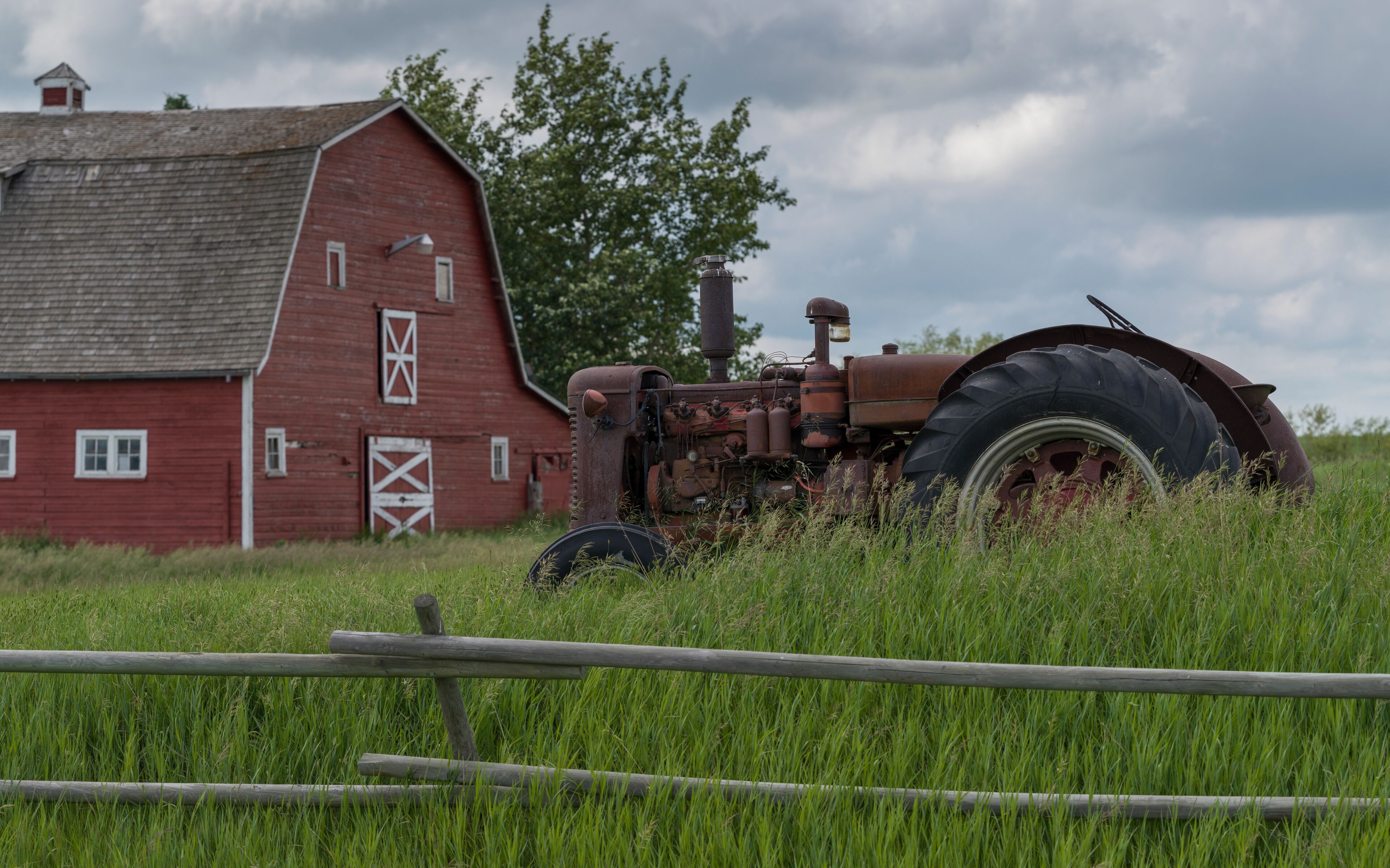 A red barn, a rusty tractor, and a grassy field.