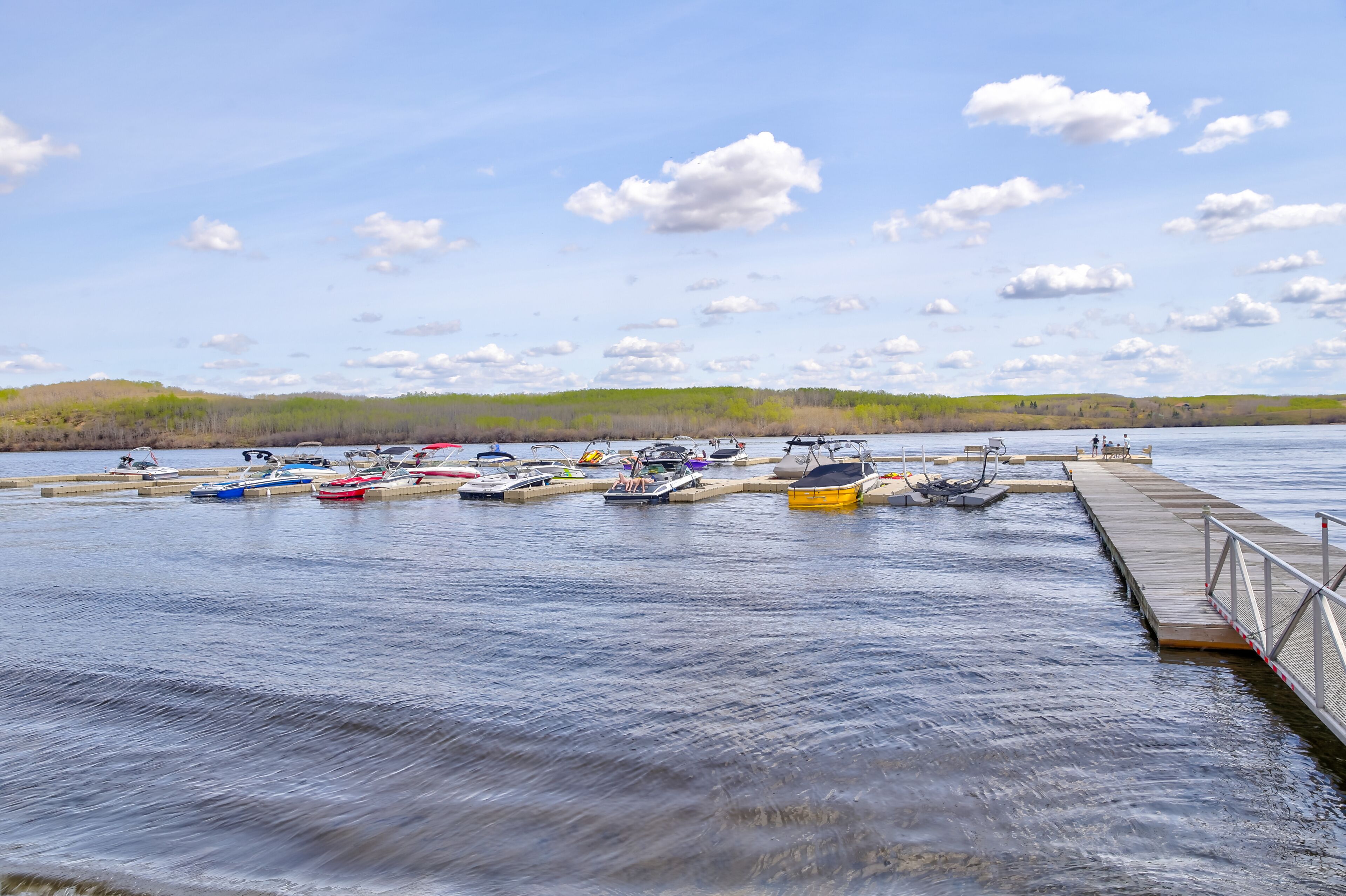 Un lago tranquilo con un muelle y varios barcos.