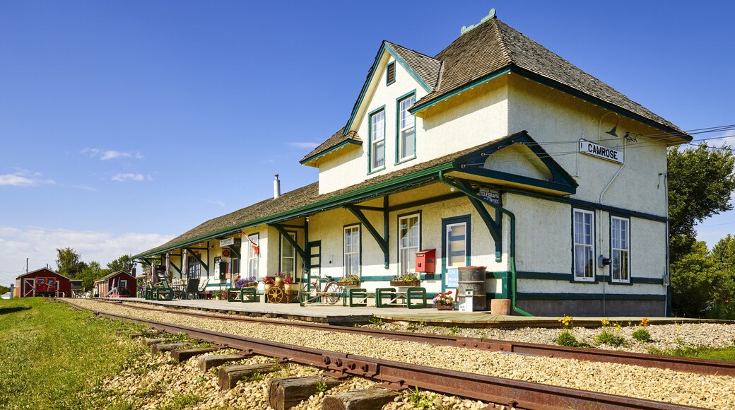 A quaint train station and decorated platform with tracks running by; Camrose, Alberta, Canada