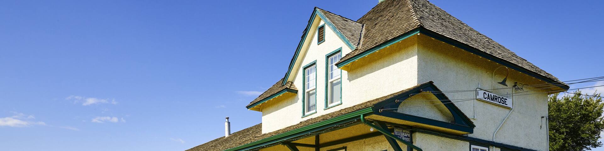 A quaint train station and decorated platform with tracks running by; Camrose, Alberta, Canada