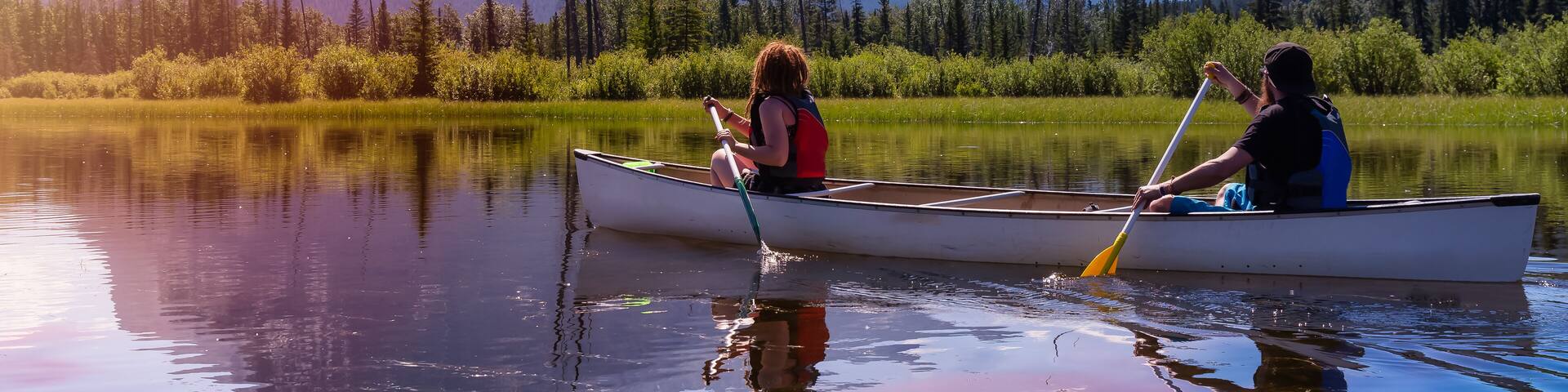 Couple adventurous friends are canoeing in a lake surrounded by the Canadian Mountains. Colorful Sunrise Sky Art Render. Taken in Vermilion Lakes, Banff, Alberta, Canada.