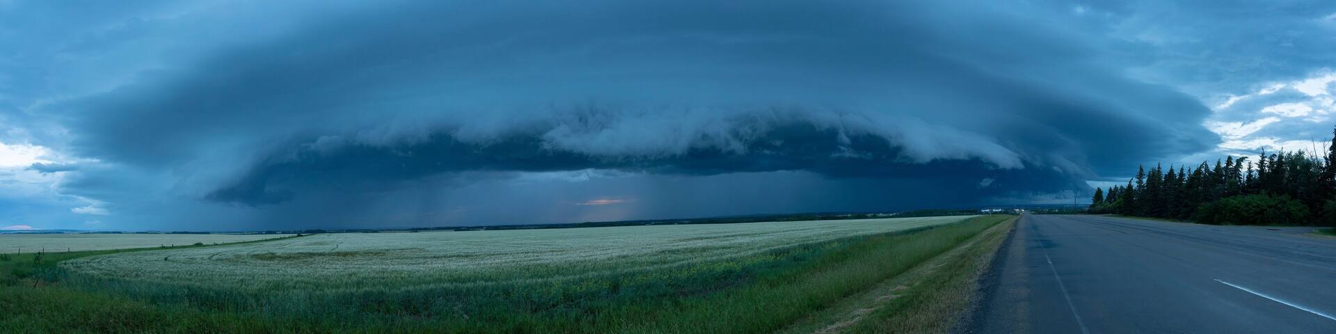 Panorama of supercell thunderstorm clouds over farmland and a country road; Grande Prairie, Alberta, Canada