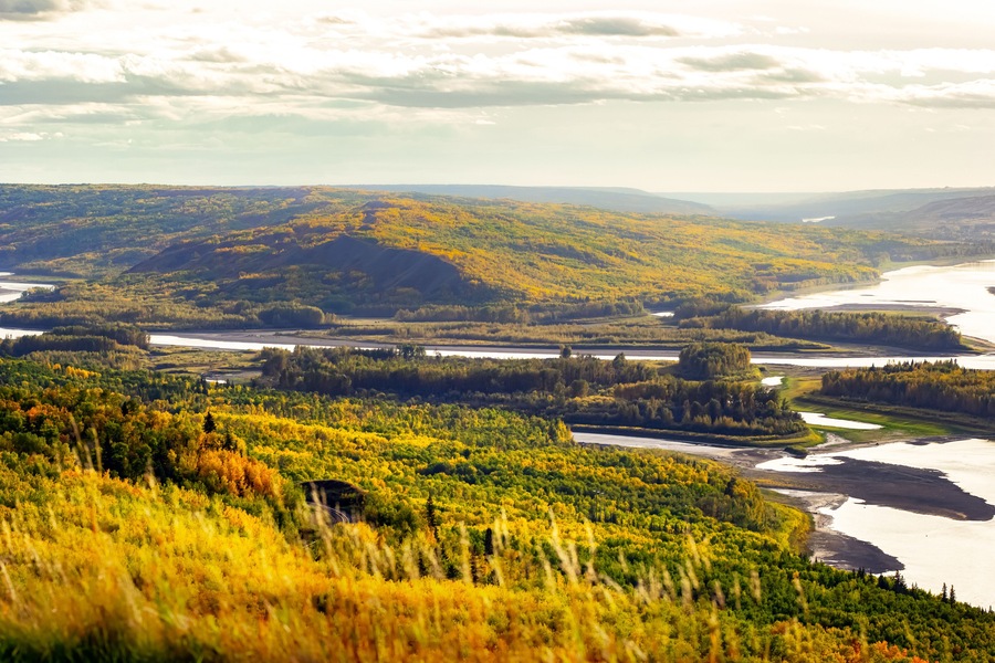 View from the hill to the river down in the valley surrounded with forests with yellow and green autumn foliage. Sagitawa lookout, Peace River, Alberta, Canada.