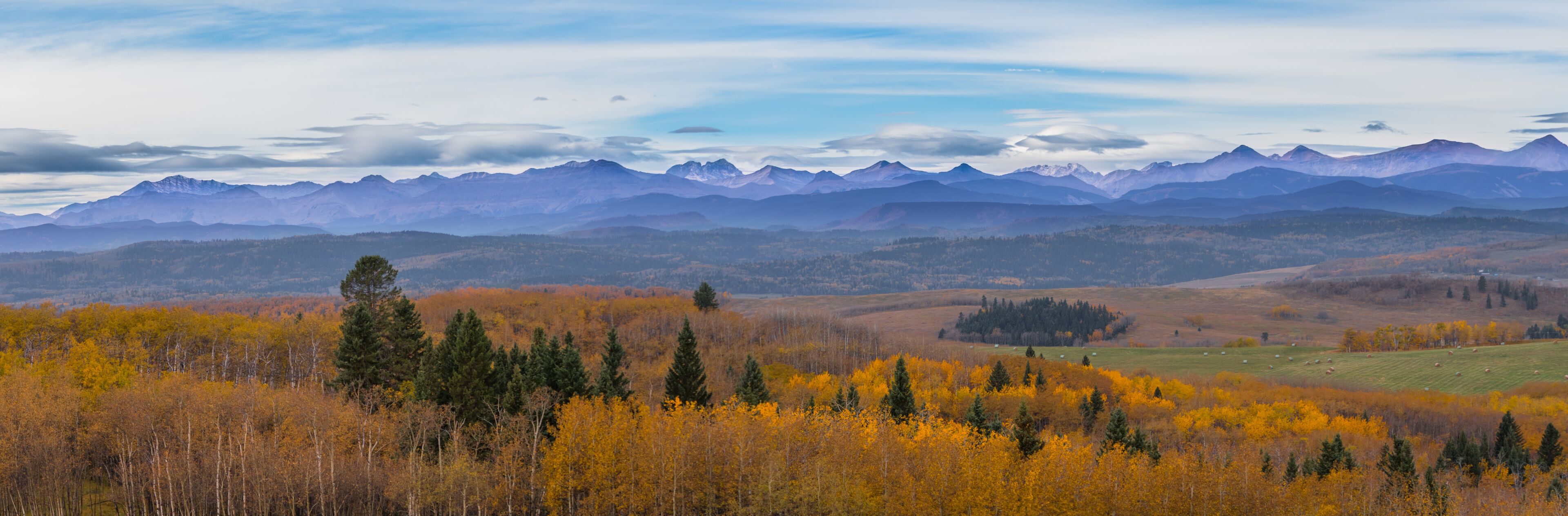 A mountainous landscape with autumn foliage and grazing fields.