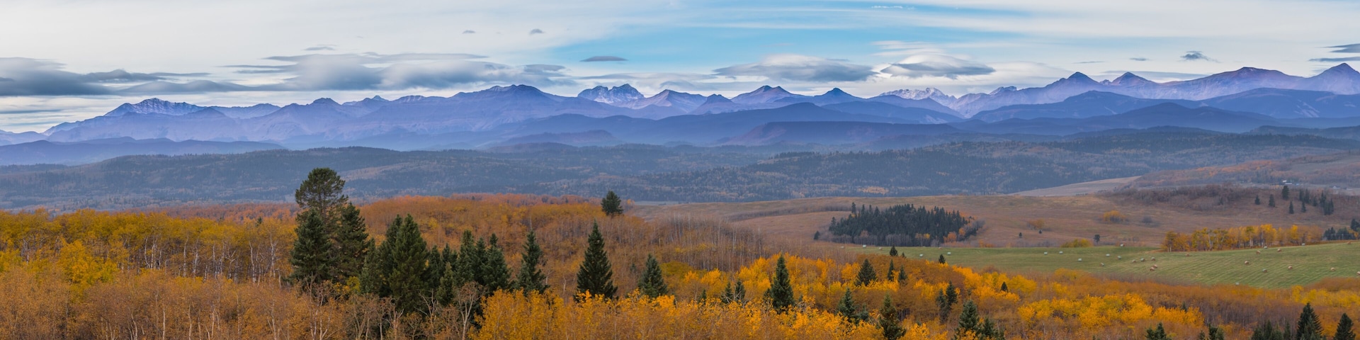 A mountainous landscape with autumn foliage and grazing fields.