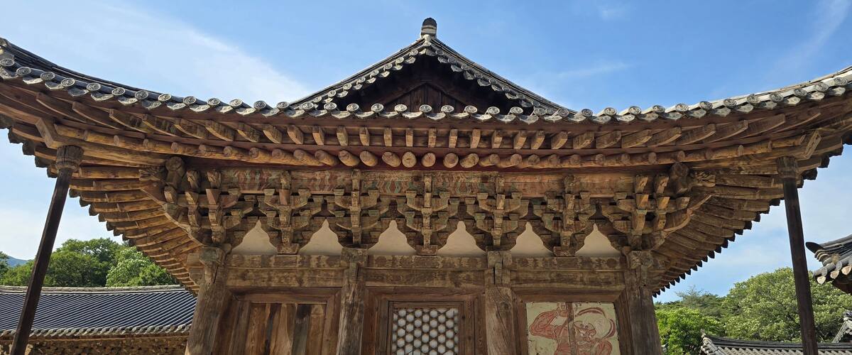 A traditional wooden structure with ornate roof tiles and a detailed mural.
