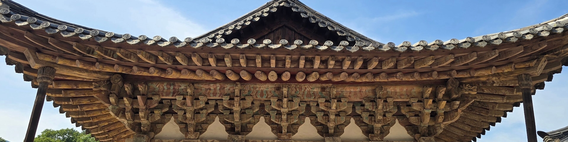 A traditional wooden structure with ornate roof tiles and a detailed mural.