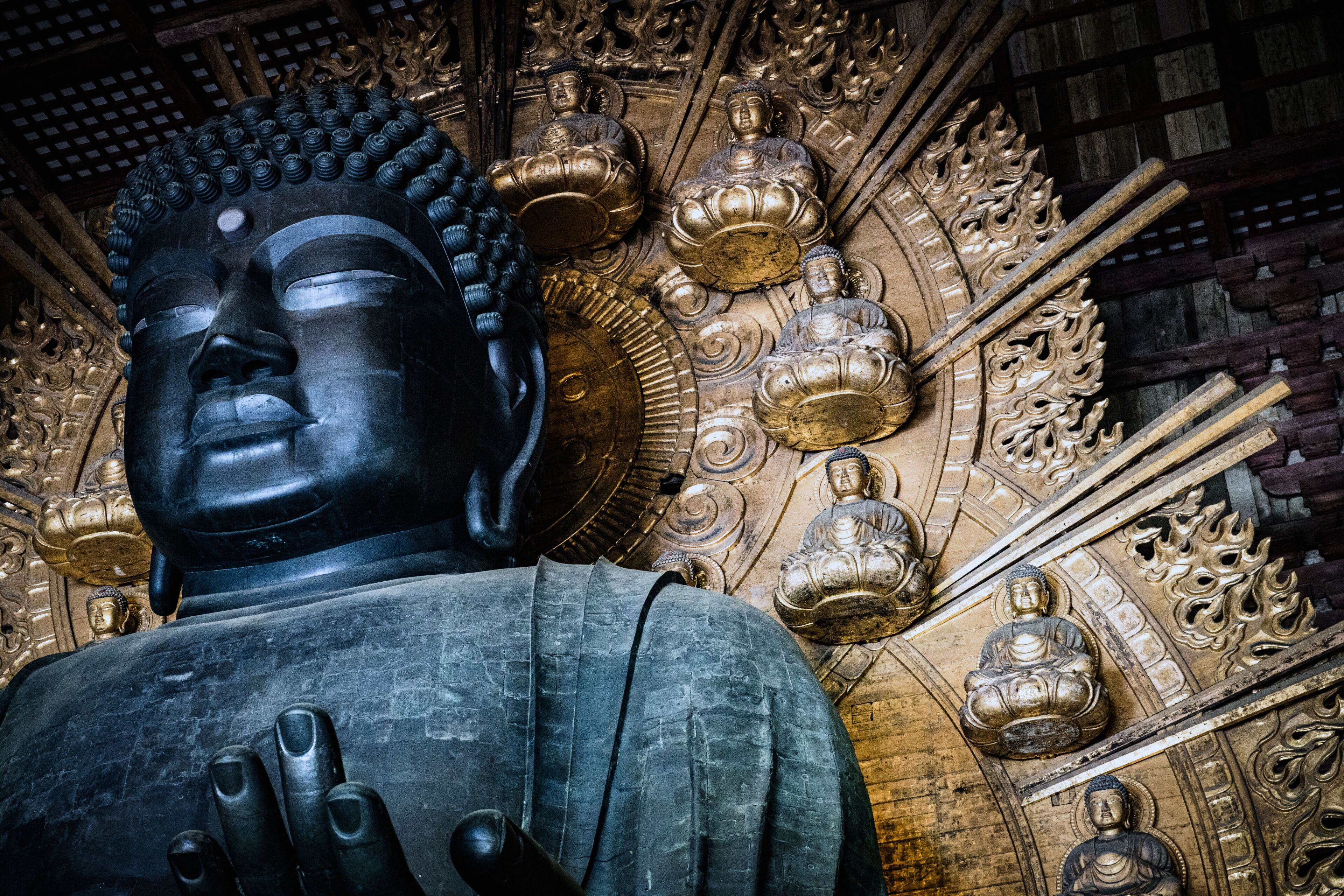 Uma grande estátua de Buda com esculturas detalhadas e detalhes dourados em um templo.