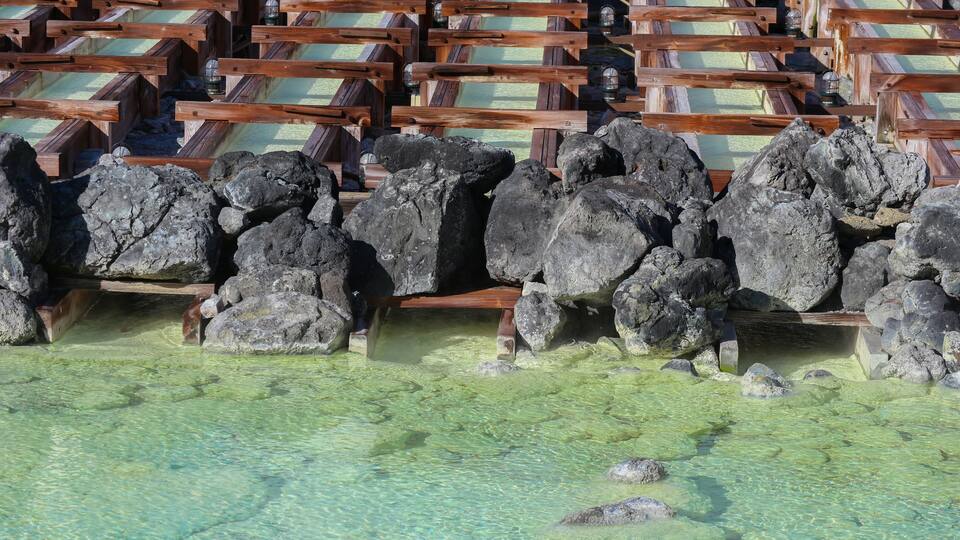 A wooden structure with benches and large rocks in a shallow water body.