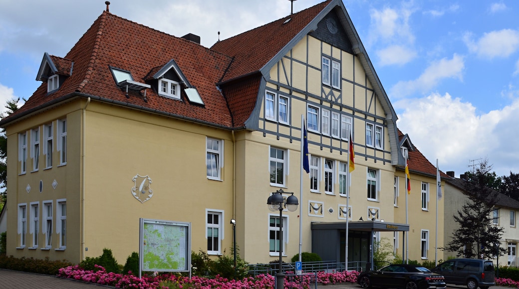 Ein gelbes Gebäude mit rotem Ziegeldach, zahlreichen Fenstern und Flaggen.