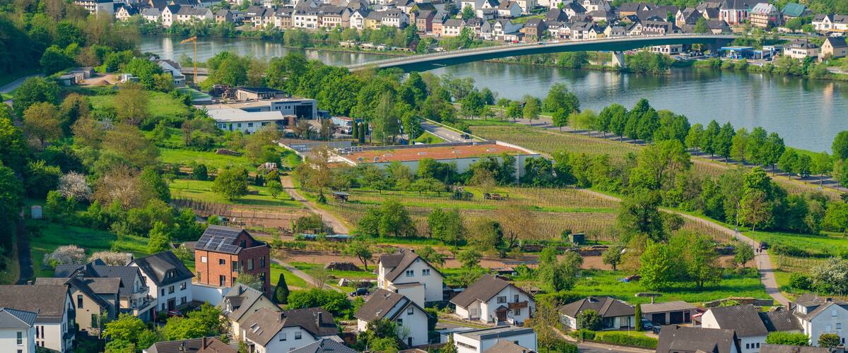 A river with a bridge, surrounded by residential houses and green fields.
