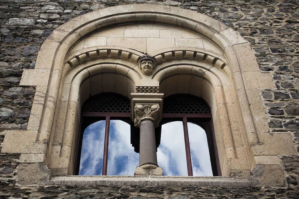 Une fenêtre en pierre, dotée d’un arc en plein cintre et d’un pilastre décoratif.