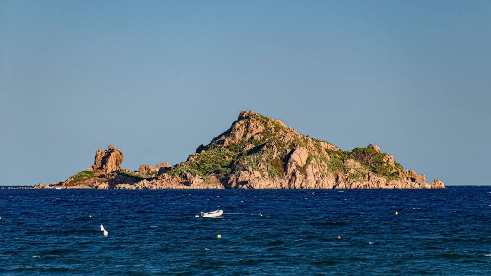 A rocky island with a clear blue sky.