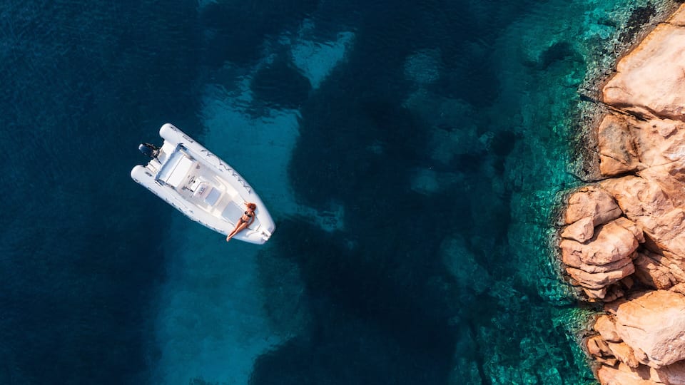 A boat on clear turquoise water near rocky coastline.