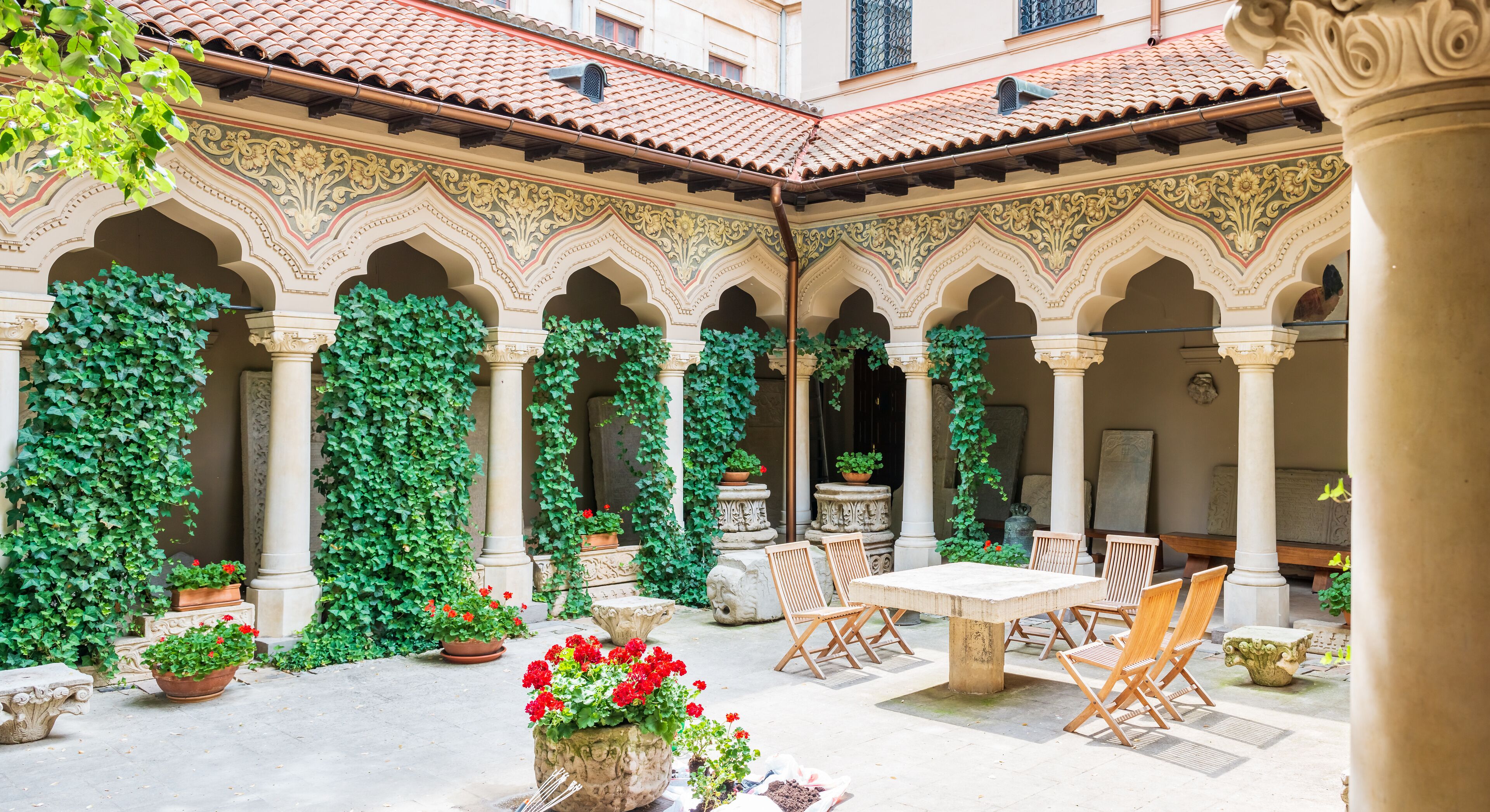A courtyard with arches, columns, and potted plants.
