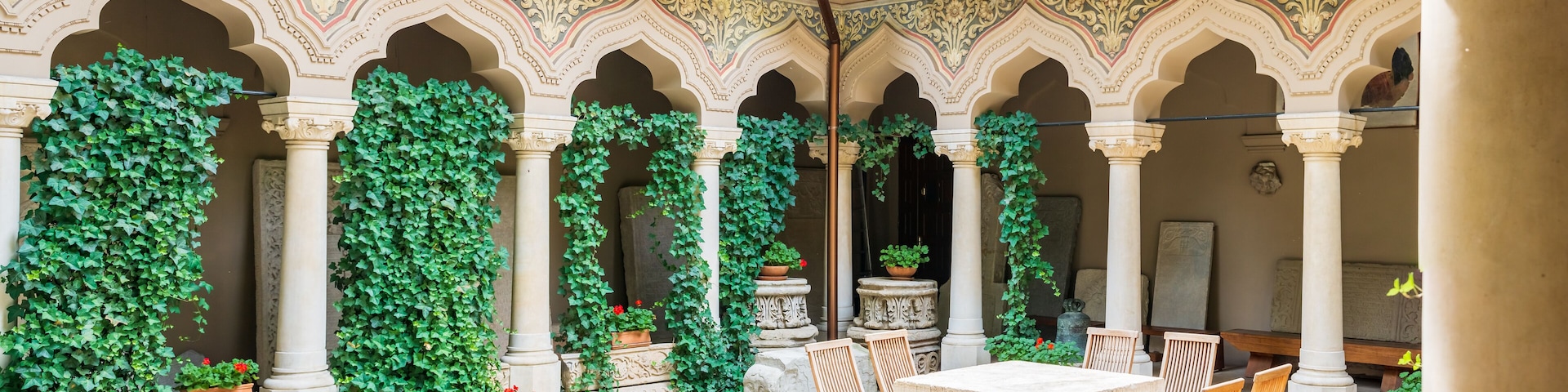 A courtyard with arches, columns, and potted plants.