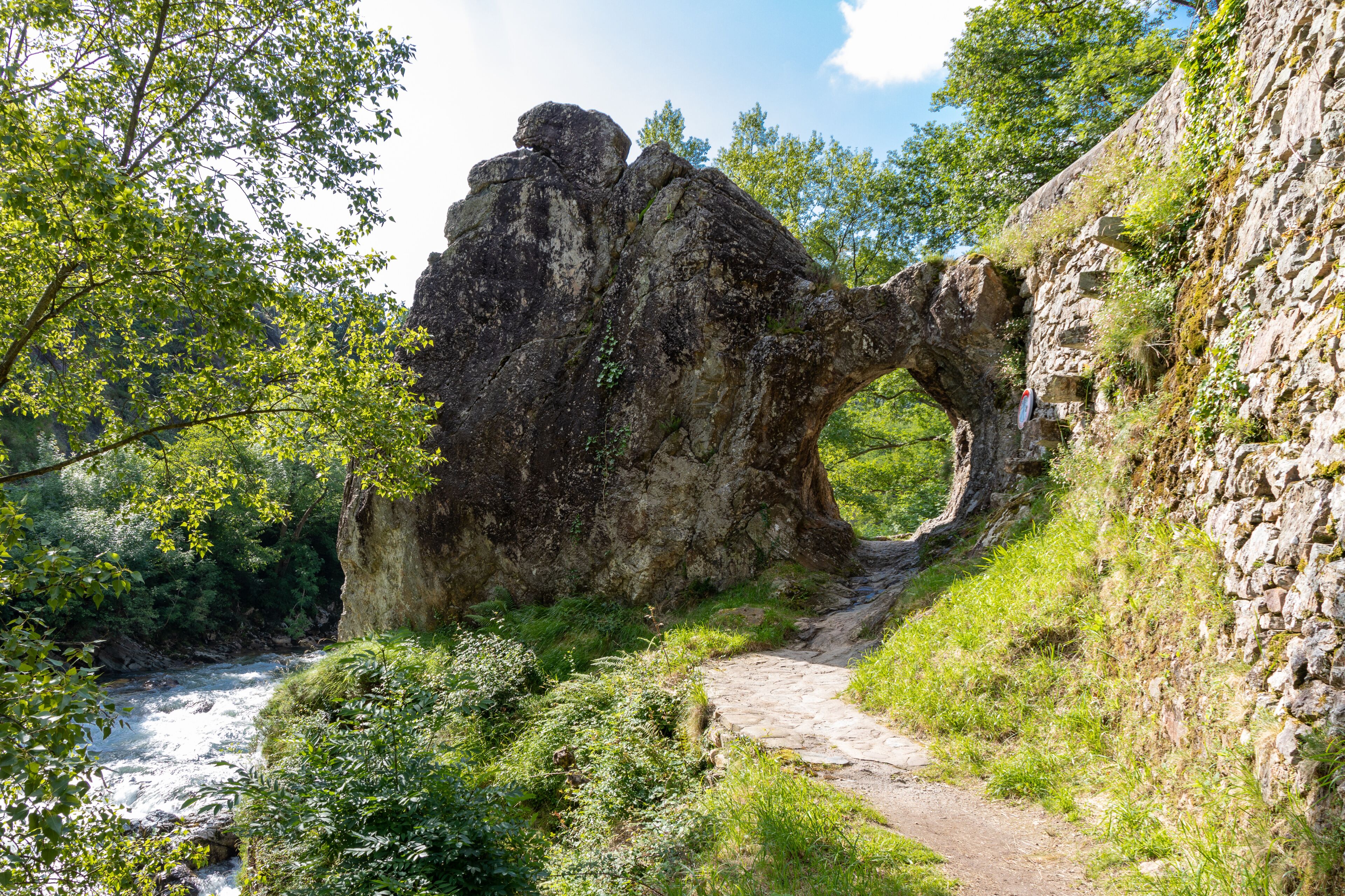 A natural rock arch formation with a path leading through it.