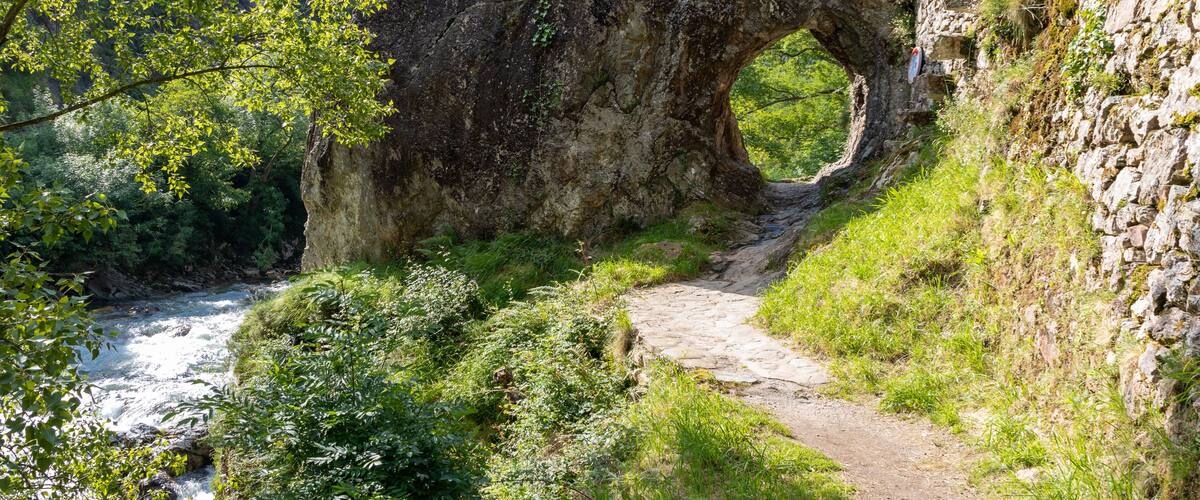 A natural rock arch formation with a path leading through it.