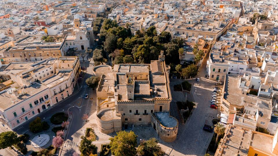 An aerial view of a historic city center with dense urban architecture, a prominent church, and a central square.
