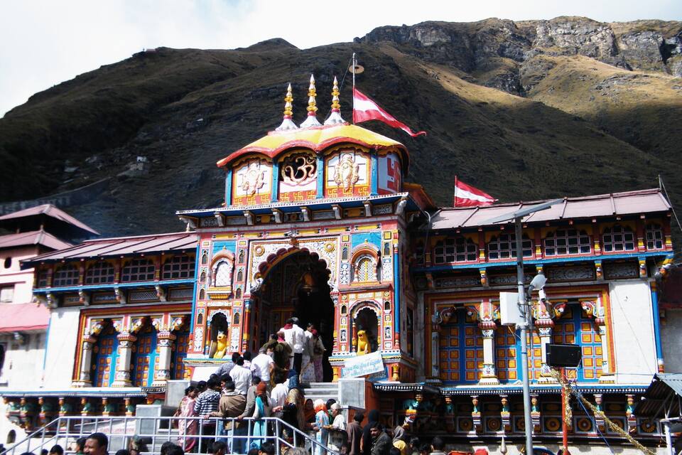 A colorful temple with intricate architecture and a mountainous backdrop.