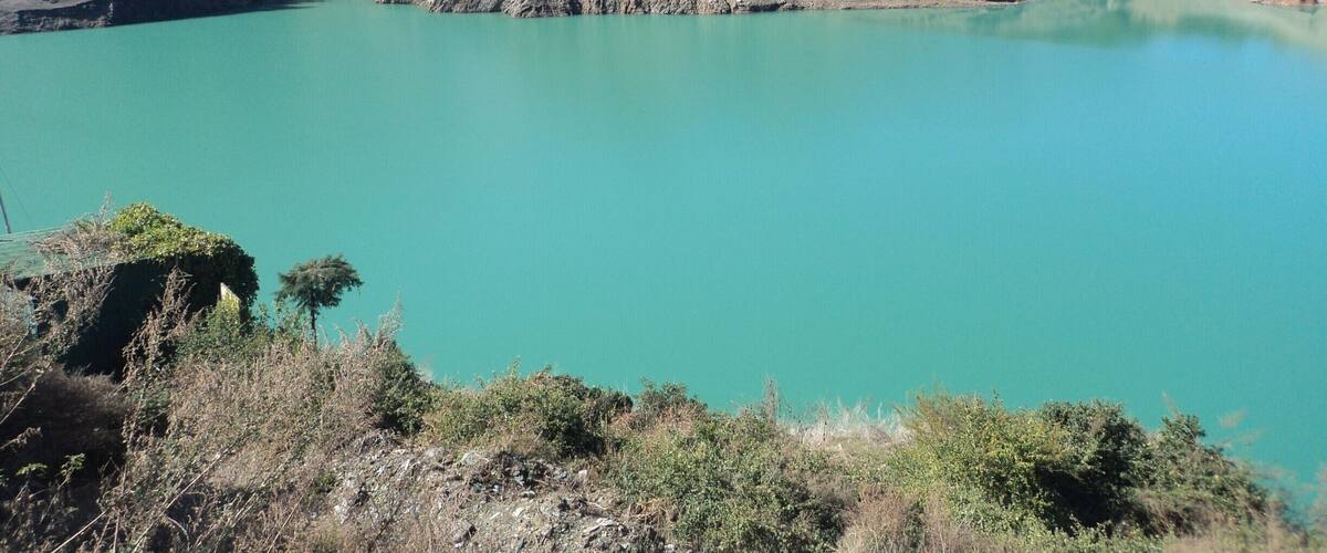 A turquoise lake surrounded by mountains and sparse vegetation.