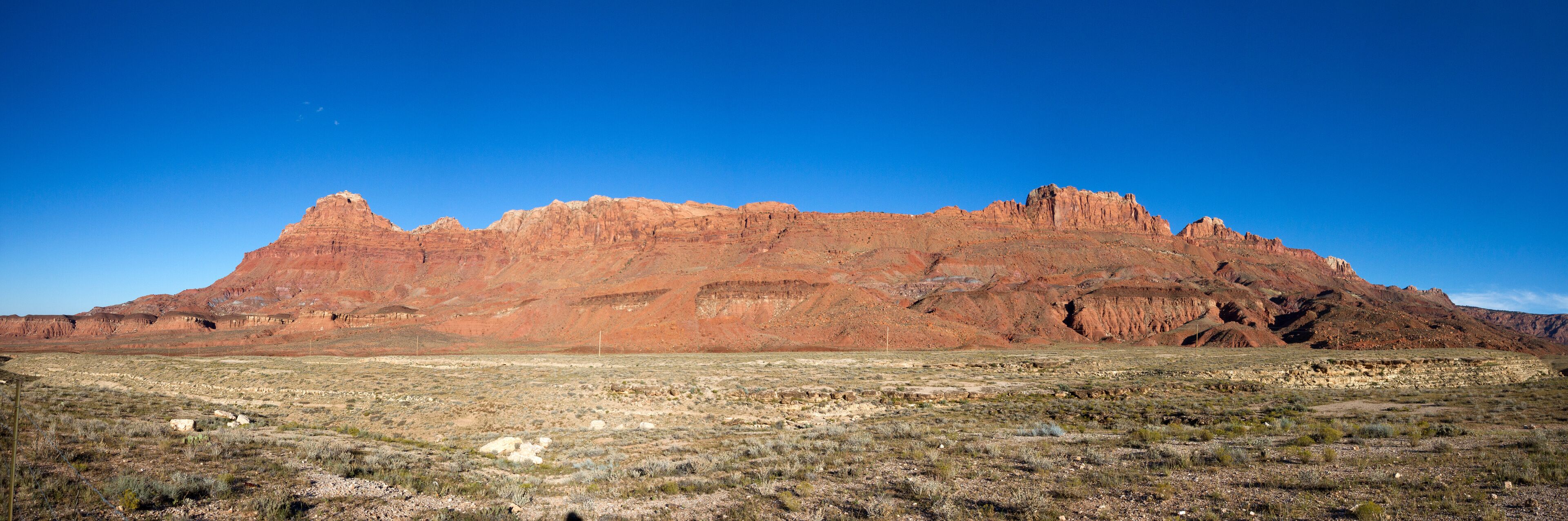 A desert landscape with a prominent red rock formation in the background.