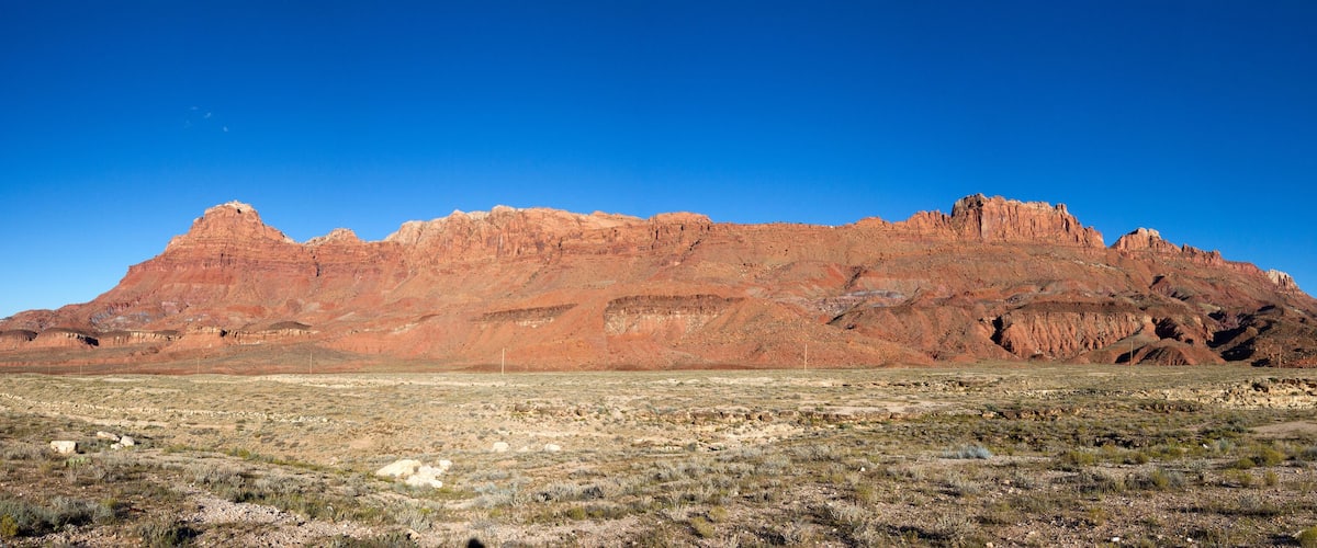 A desert landscape with a prominent red rock formation in the background.