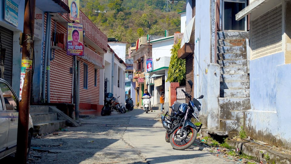 A narrow street lined with buildings, some with signs and posters, and a motorcycle parked on the side.