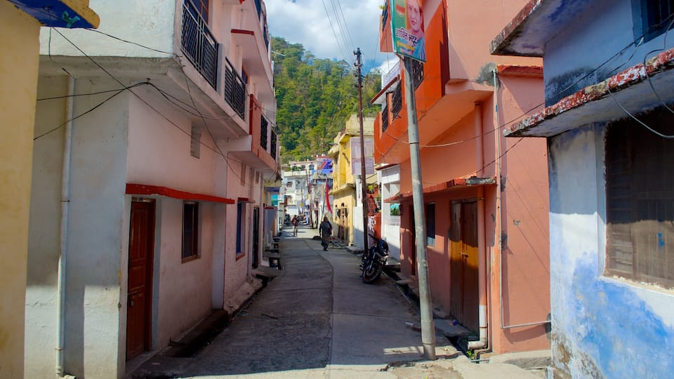 A narrow street lined with colorful buildings, a motorcycle parked on the side, and a person walking in the distance.