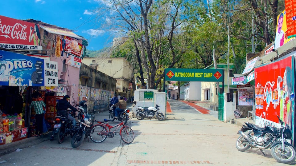 A street with shops, motorcycles, and a sign for Kathgodam Rest Camp.