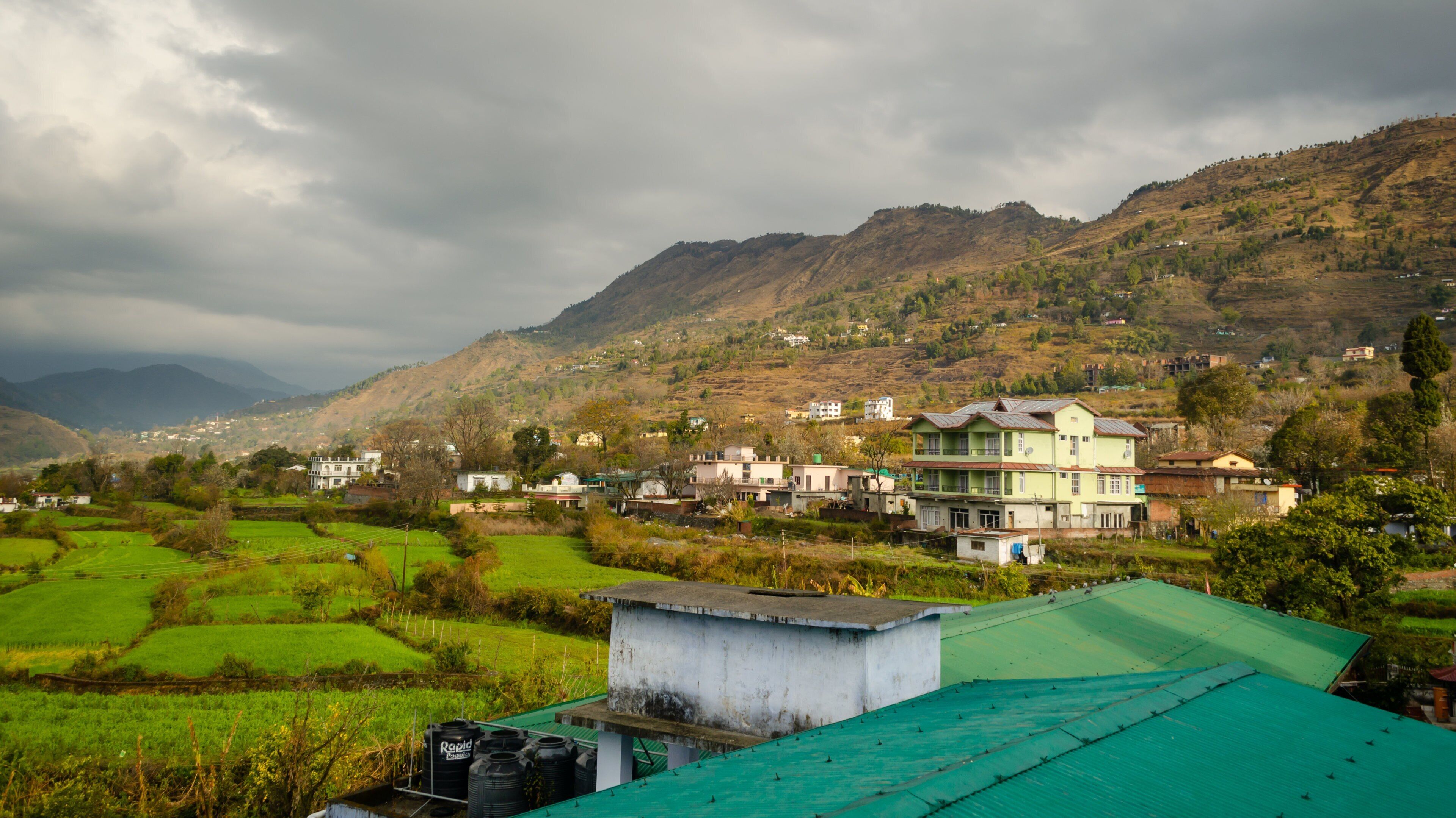 A rural village with green fields and a large building with a green roof.