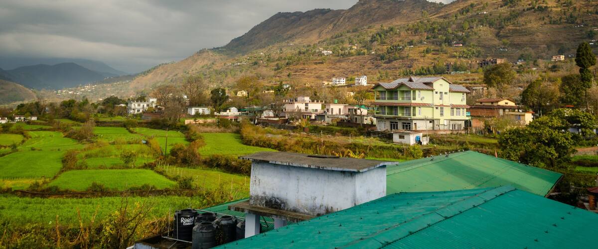 A rural village with green fields and a large building with a green roof.