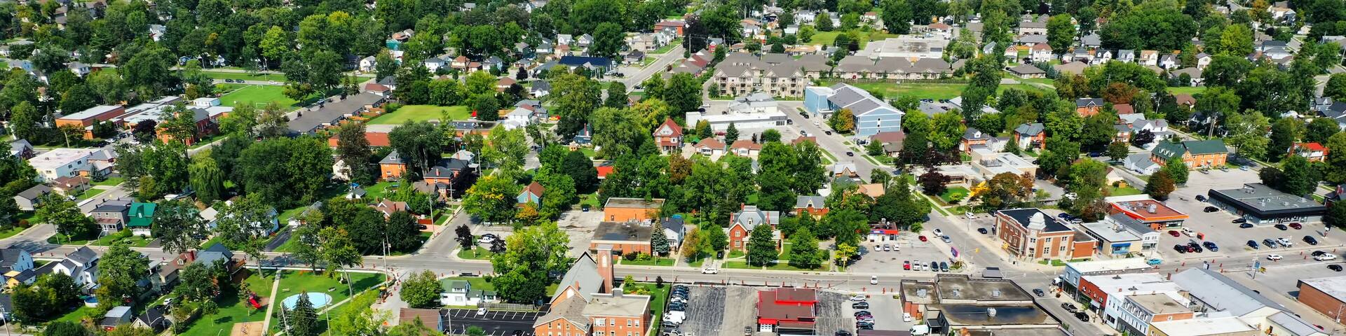 An aerial view of a town with a mix of residential and commercial buildings, roads, and green spaces.