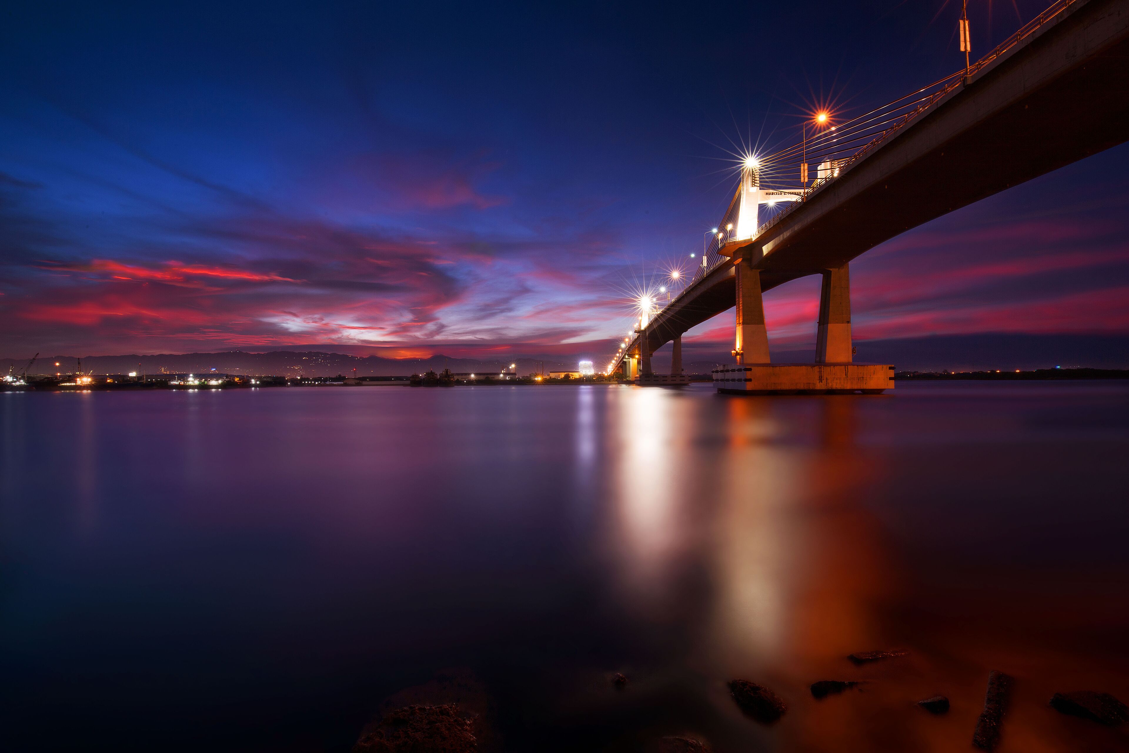 A bridge at twilight with a reflection on the water.