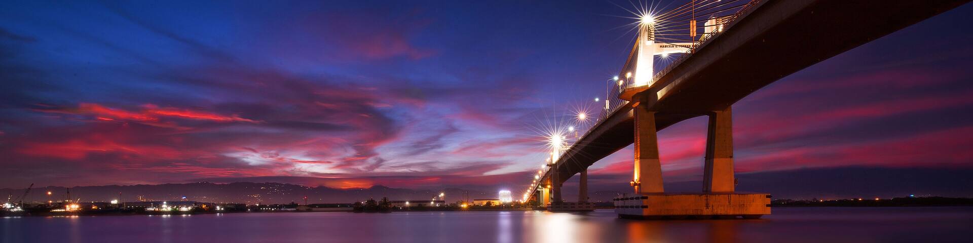 A bridge at twilight with a reflection on the water.