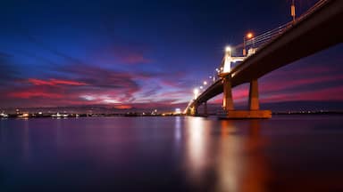Un puente al atardecer con su reflejo en el agua.