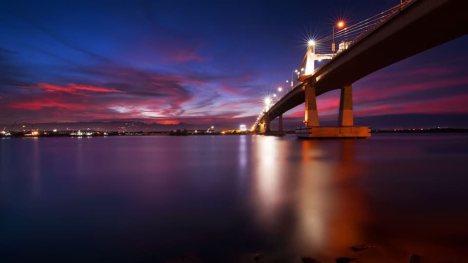 A bridge at twilight with a reflection on the water.