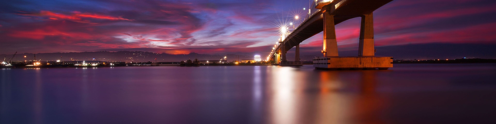 Eine Brücke im Zwielicht mit Spiegelung im Wasser.