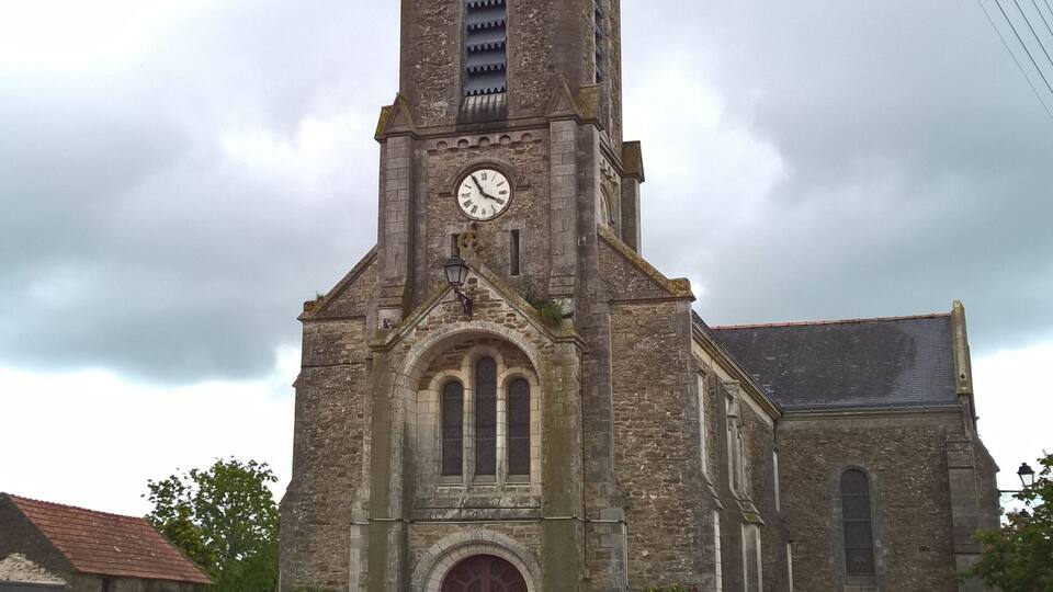 A church with a tall bell tower, a clock, and a red door.