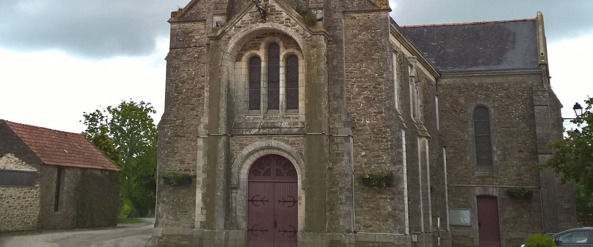A church with a tall bell tower, a clock, and a red door.