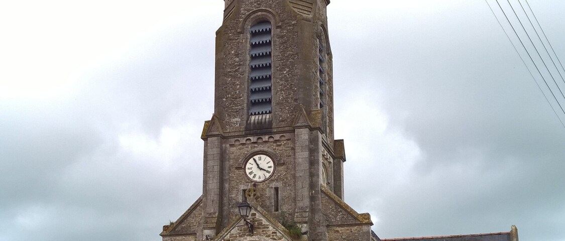 A church with a tall bell tower, a clock, and a red door.