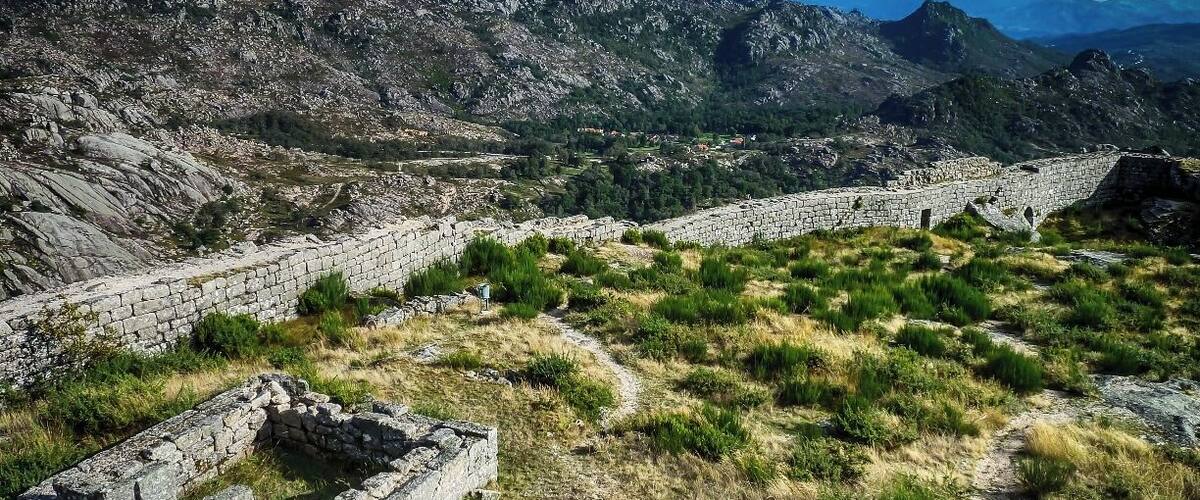 Ancient stone ruins amidst a mountainous landscape with a clear sky.
