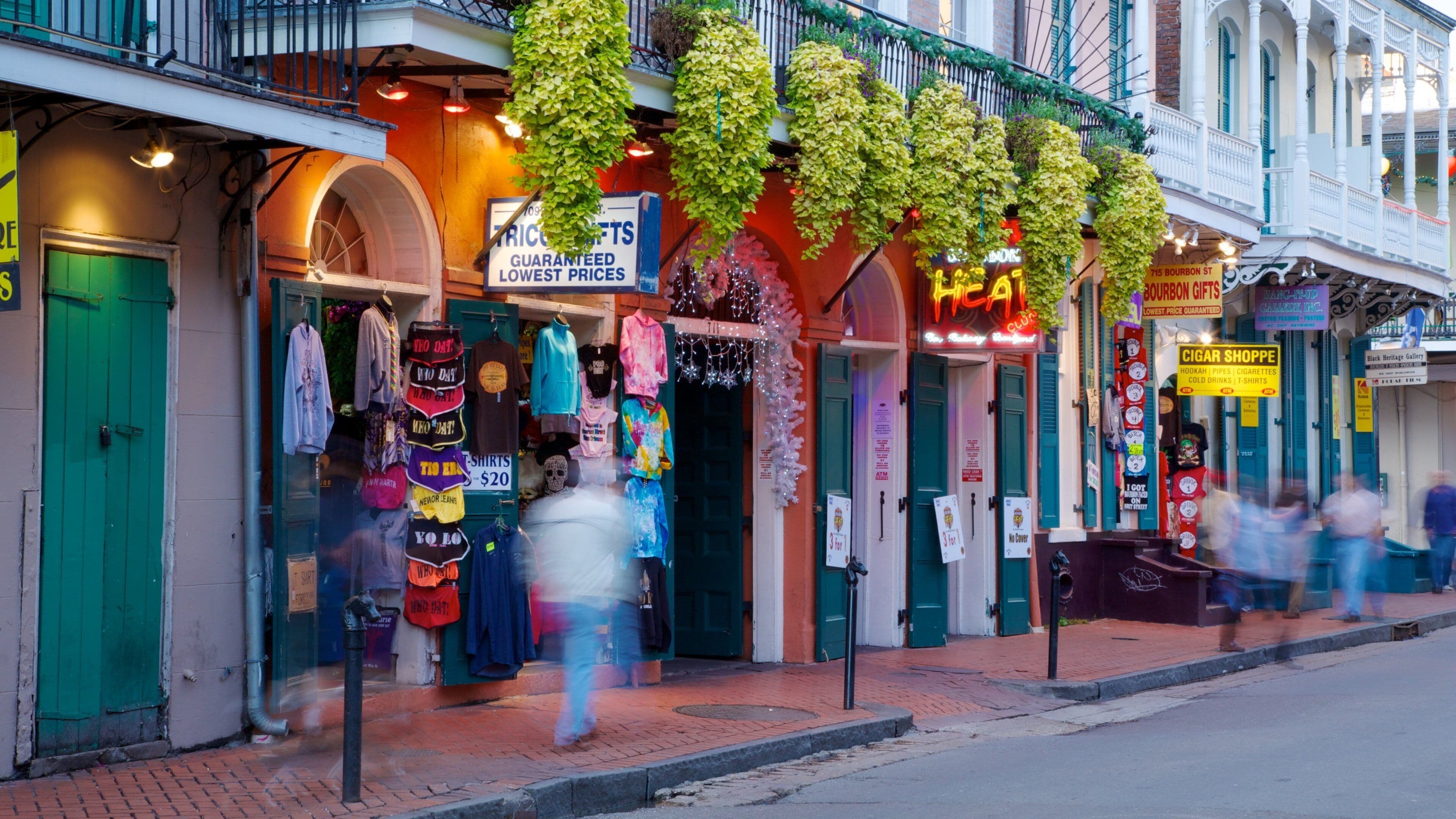 Vibrant atmosphere of Bourbon Street with shops, crowds, and greenery in New Orleans