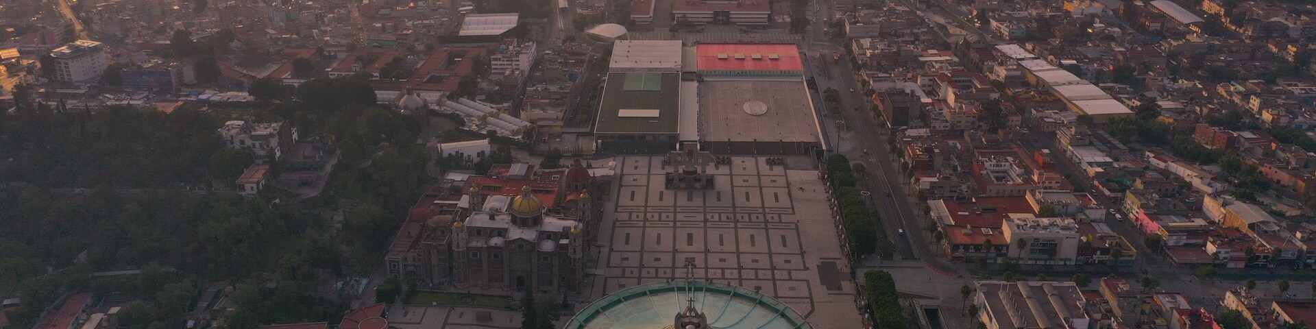 Vista aérea de uma cidade com um edifício circular imponente, com cúpula, e um grande edifício retangular com telhado vermelho.
