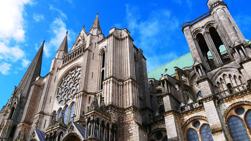 Une cathédrale gothique, caractérisée par ses arcs brisés, ses grandes fenêtres à vitraux et son flèche élancée.