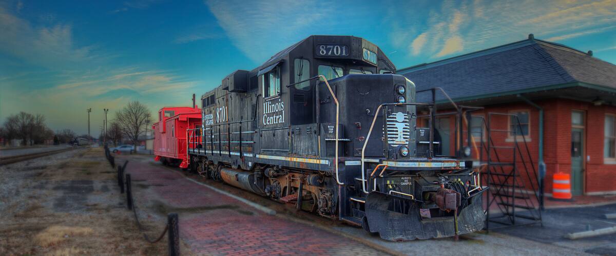 A black and red train with the number 8701 at a train station.