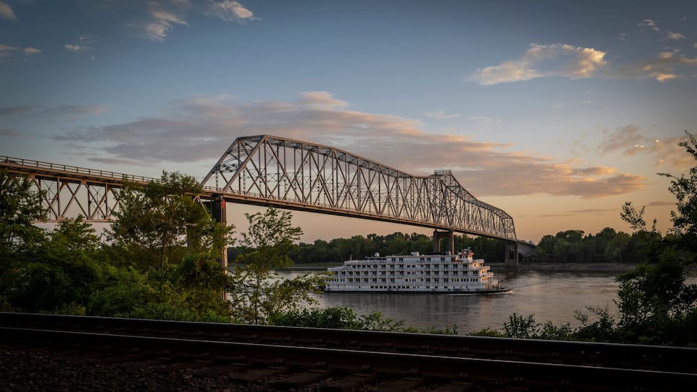 View of a serene sunset over the Mississippi River with a bridge and a boat, Chester, United States.
